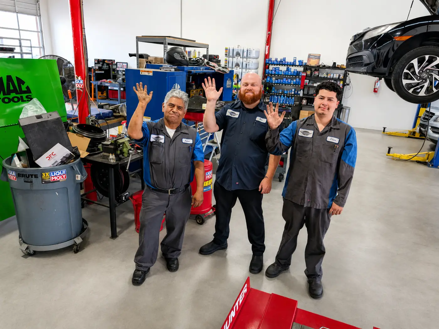 Three Super Service of Corona Hills technicians waving hello from the shop floor